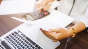 A photo of a business person examining a printed report with a laptop