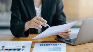 Woman at desk with papers and laptop.