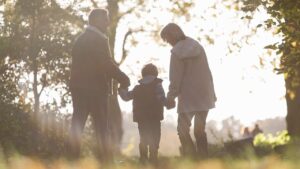 Two older people walk outside with a child between them