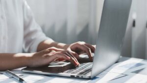 Hands typing on a laptop