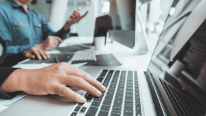 Two employees discuss over a computer.