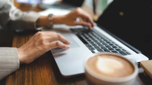 A business woman typing on a laptop at a coffee shop