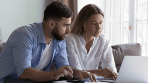 A man and a woman looking at a computer together doing taxes.