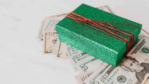 A green sparkly gift box sitting on top of paper money