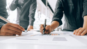 People wearing gray shirts writing on a piece of paper with a gray and orange chart.