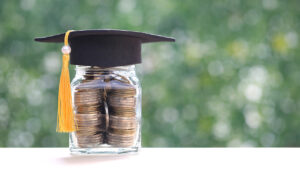 A jar of coins with a graduation cap sitting on top.