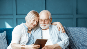 Couple sitting on a couch looking at a tablet.