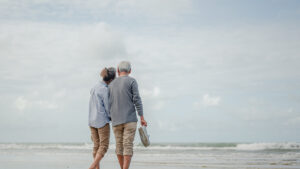 An older couple walking on the beach.
