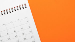 An open white calendar on an orange background.