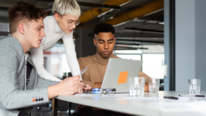 Group of three people looking at a laptop