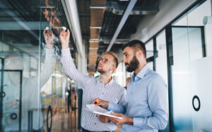 Two business partners using a clear white board.