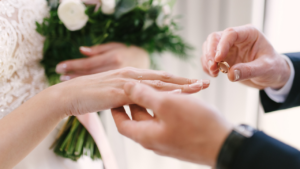 Hand putting a wedding band on another hand